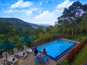 two people sitting at a table next to a swimming pool at Grand Hills kandy in Kandy
