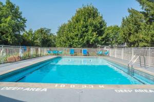 a swimming pool with blue chairs and a fence at Rodeway Inn Fallsview in Niagara Falls