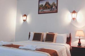 a bedroom with a bed with two lamps and a picture on the wall at Khampiane Hotel in Vientiane