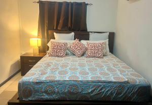 a bedroom with a bed with pillows and a lamp at Manutapu Lodge in Tongatapu