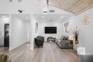 a living room with a couch and a tv on a wall at Sunset Escape in Summerland Point