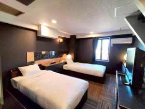 a hotel room with two beds and a television at 富士OUTLET Hotel in Gotemba