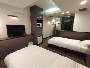 a hotel room with two beds and a flat screen tv at 富士OUTLET Hotel in Gotemba