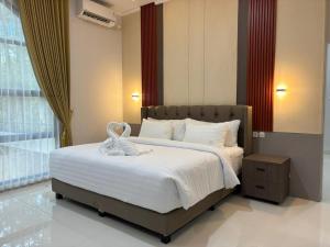 ein Schlafzimmer mit einem großen Bett, auf dem ein Handtuch liegt in der Unterkunft BBIB Suites in Wonorejo