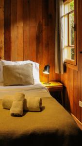 a bedroom with a bed with a lamp and a window at Wesley House Hosteria Boutique in San Martín de los Andes