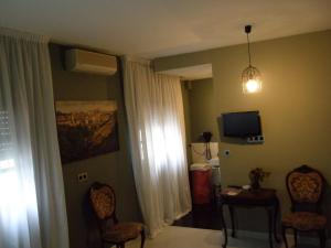 a living room with two chairs and a tv and a room at Hostal San Francisco in Cuéllar