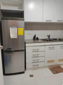 a kitchen with a stainless steel refrigerator and white cabinets at Astoria Plaza Residential in Manila