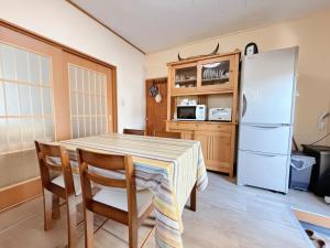 eine Küche mit einem Tisch und einem Kühlschrank in der Unterkunft 叶 in Nishikichō
