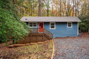 a blue tiny house with a deck in the woods at Three Trees Retreat in Ellijay