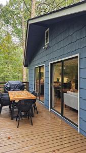 a blue house with a table and chairs on a deck at Three Trees Retreat in Ellijay