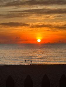two people swimming in the ocean at sunset at Pearl Oceanic Resort - Trincomalee in Trincomalee