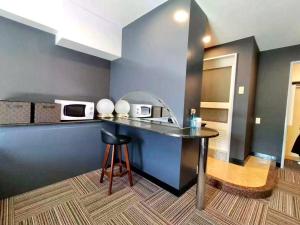 a kitchen with a counter with two microwaves and a stool at 富士OUTLET Hotel in Gotemba