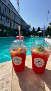 two drinks in plastic cups sitting next to a pool at Центральна Садиба in Kryzhanivka
