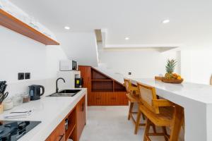 a kitchen with white counters and wooden cabinets at Villa Ombak - 1BR Private Luxury Villa 150m from Seseh Beach in Canggu