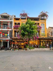 a large yellow building with flowers on top of it at Hoianan Boutique Hotel in Hoi An