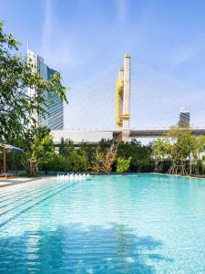 a large pool of water with a bridge in the background at Luxury Riverside Condo with riverside pool in Bangkok
