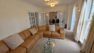 a living room with a brown couch and a glass table at First Class Luxurious Apartment London Finchley in Brent Station
