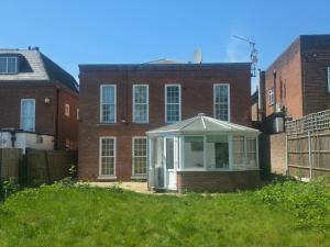 a house with a conservatory in front of a brick building at First Class Luxurious Apartment London Finchley in Brent Station