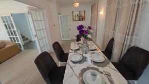 a dining table with chairs and a vase of purple flowers at First Class Luxurious Apartment London Finchley in Brent Station