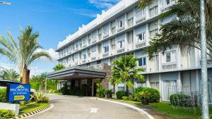 a large white building with palm trees in front of it at Microtel Inn & Suites by Wyndham San Fernando in San Fernando