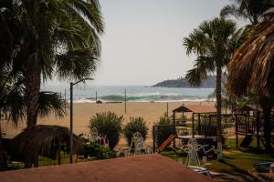 a beach with chairs and palm trees and the ocean at Bungalows Puerta de Sol in Brisas de Zicatela
