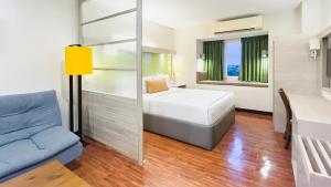 a bedroom with a bed and a blue couch at Microtel Inn & Suites by Wyndham San Fernando in San Fernando