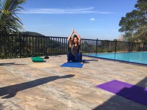 a woman sitting in a yoga pose next to a pool at Grand Hills kandy in Kandy