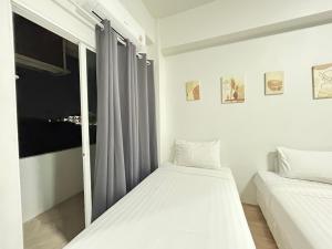 ein weißes Schlafzimmer mit zwei Betten und einem Fenster in der Unterkunft Comfy hotels คอมฟี่โฮเทล in Suvarnabhumi Airport