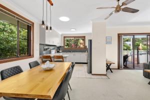 a kitchen and dining room with a wooden table and chairs at Brodie Getaway in Coffs Harbour