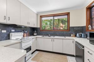 a kitchen with white cabinets and a window at Brodie Getaway in Coffs Harbour