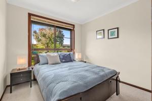 a bedroom with a large bed and a window at Brodie Getaway in Coffs Harbour