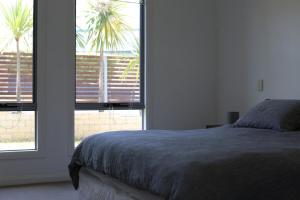 a bedroom with a bed and a window with a palm tree at Azure in Bridport
