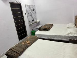 two beds in a small room with a door at Dixit's Residency in Godarpura