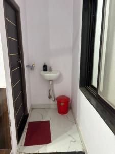 a bathroom with a sink and a red bucket at Dixit's Residency in Godarpura