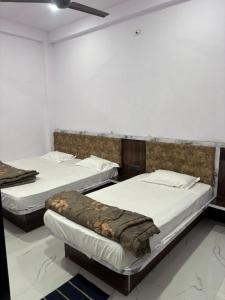 two beds in a room with white walls at Dixit's Residency in Godarpura