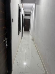 a hallway with a white tile floor in a hallway at Dixit's Residency in Godarpura