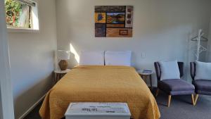 a bedroom with a bed and two chairs at Lodges On Pearson Unit 1 in Cromwell