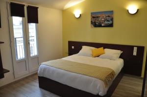 a bedroom with a large bed with yellow pillows at Massilia hôtel in Marseille