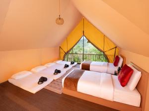 three beds in a room with a window at Lù Yīng Retreats in Bukit Tinggi