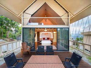a room with a bed and chairs on a deck at Lù Yīng Retreats in Bukit Tinggi