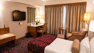 a hotel room with a bed and a desk at Pride Plaza Hotel, Ahmedabad in Ahmedabad