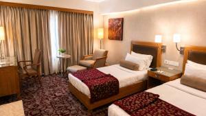a hotel room with two beds and a chair at Pride Plaza Hotel, Ahmedabad in Ahmedabad +75 photos
