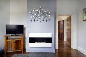 a living room with a television and a fireplace at Historic Getaway in Launceston