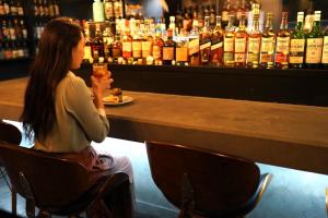 a woman sitting at a bar holding a drink at Business Inn Norte 2 in Sapporo