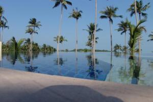 a pool of water with palm trees and the ocean at Kalara Gardens in Ban Bang Po