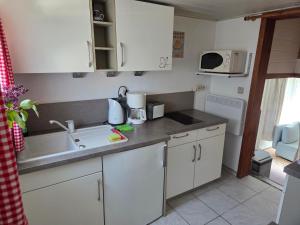 a kitchen with white cabinets and a sink at Ferienhaus Olbersdorf in Olbersdorf +11 photos