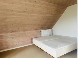 a bedroom with wooden walls and a white bed at Family private house in Brovst