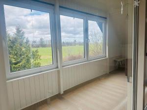 a room with three windows with a view of a field at Family private house in Brovst