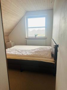 a bed in a room with a window at Family private house in Brovst +2 photos
