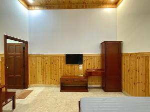 a room with a tv on a wall and a bed at Nhà Nghỉ Thi Anh in Ấp Bia